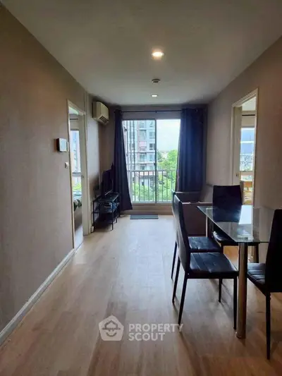 Modern living room with glass dining table and balcony view in urban apartment.