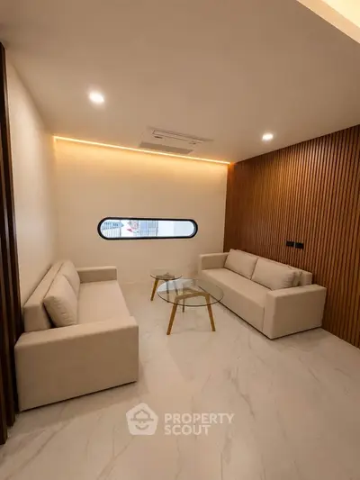 Modern living room with minimalist design, featuring two beige sofas and a glass coffee table.