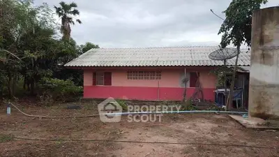 Charming rural house with pink exterior and lush greenery, perfect for serene living.