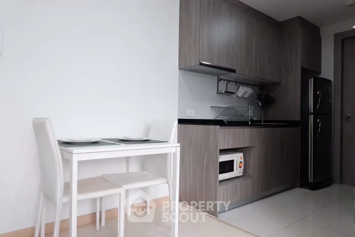 Modern kitchen with sleek cabinetry and compact dining area in a stylish apartment.