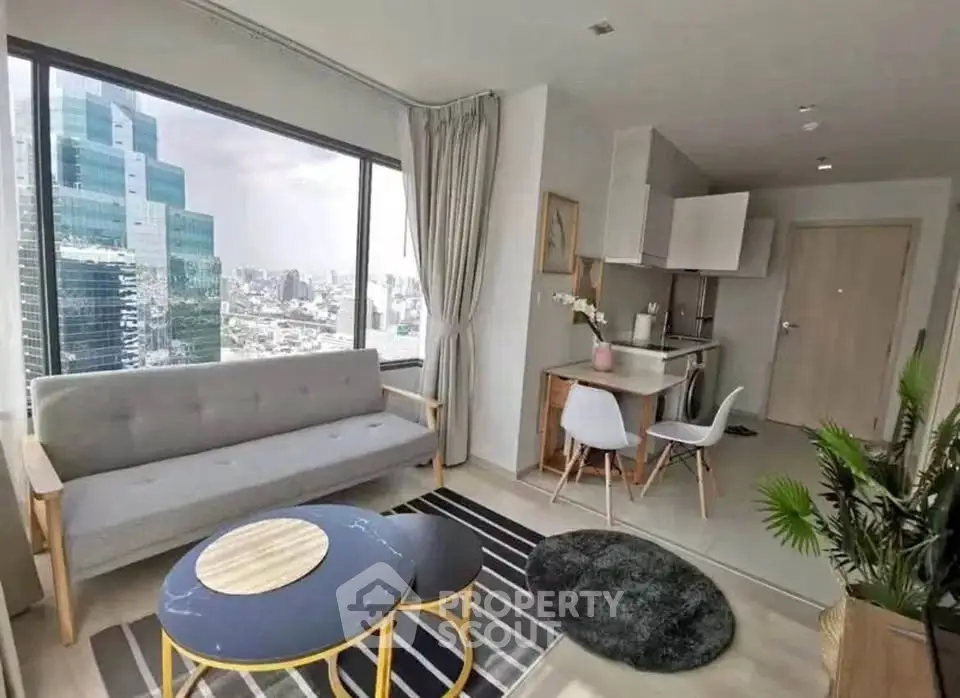 Modern living room with city view, stylish furniture, and open kitchen layout in high-rise apartment.