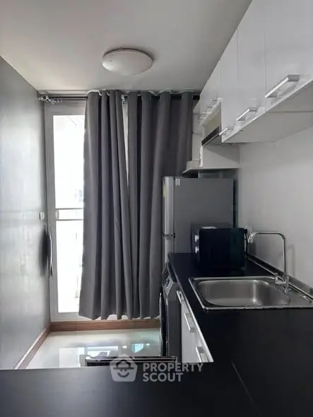 Modern compact kitchen with sleek black countertops and stainless steel appliances.