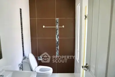 Modern bathroom with sleek design and contemporary fixtures, featuring a stylish tiled wall and natural light.