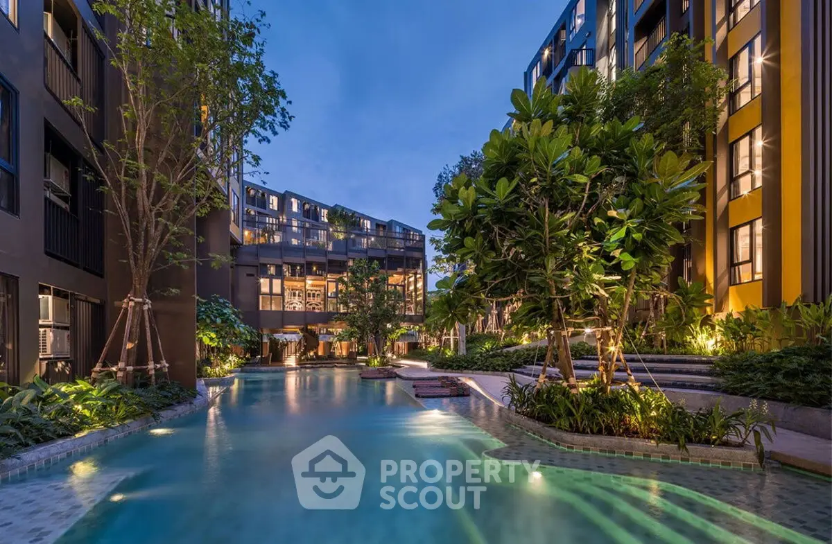 Luxurious apartment complex with stunning pool and lush landscaping at twilight.