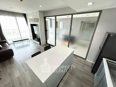 Modern open-layout living room with sleek kitchen island and large windows for natural light.