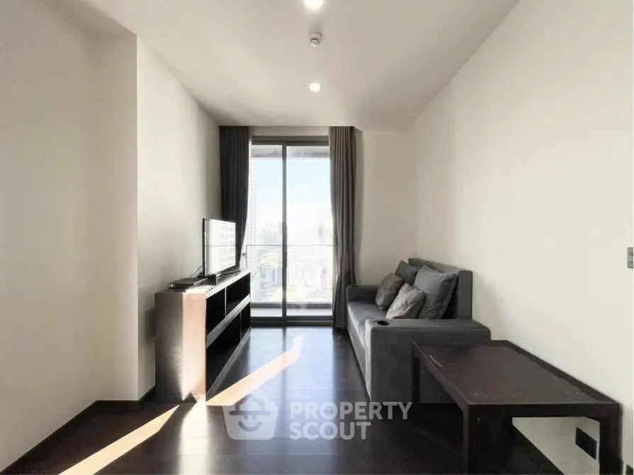 Modern living room with sleek furniture and large window offering city view.