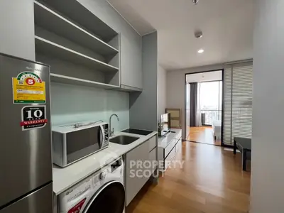 Modern kitchen with appliances and open layout leading to a bright living area with balcony view.