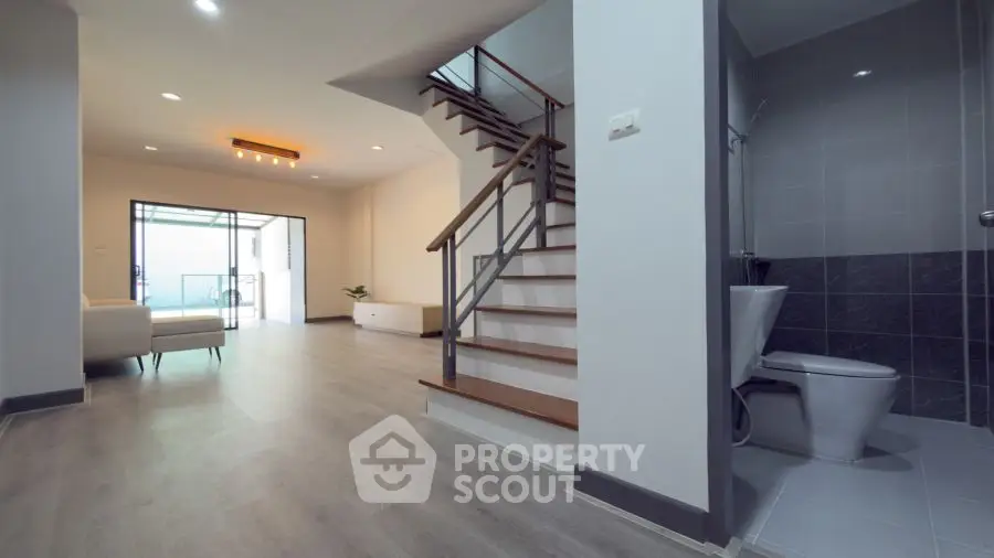 Spacious modern interior with open living area and staircase, featuring sleek design and natural light.