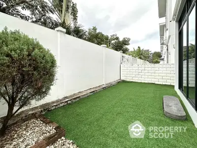 Charming backyard with artificial grass and privacy wall in modern home