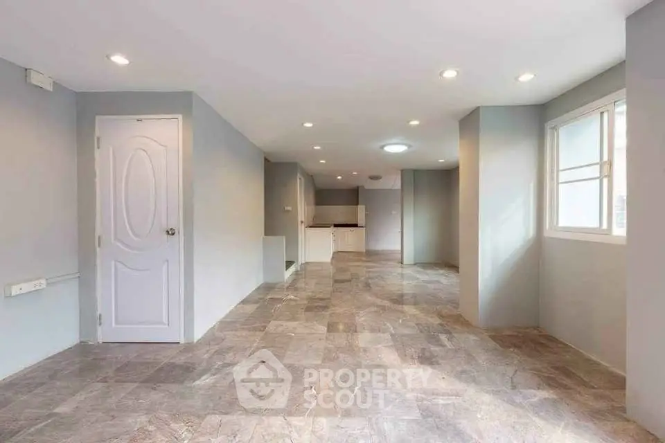 Spacious open-plan living area with modern tiled flooring and ample natural light.