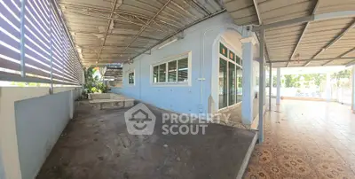 Spacious covered outdoor area with tiled flooring and blue walls, perfect for gatherings.