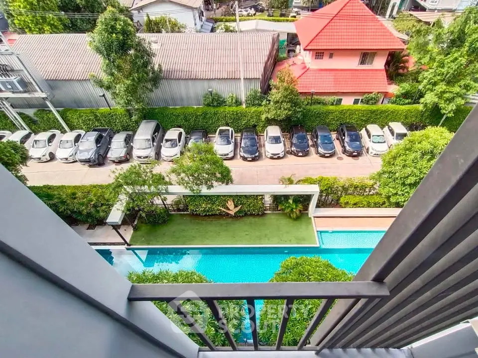 Stunning aerial view from balcony overlooking pool and parking area in modern residential complex.