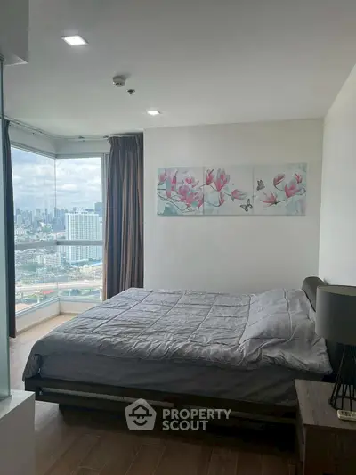 Modern bedroom with city view and elegant decor in high-rise apartment.