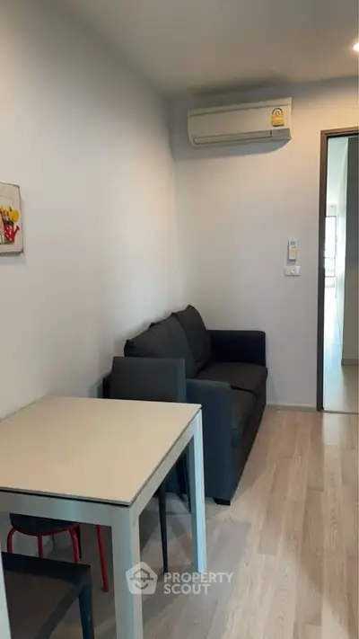Cozy living room with modern sofa and dining table, featuring sleek air conditioning unit.
