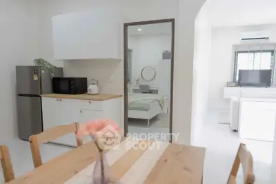 Cozy open-plan kitchen and dining area with view into modern bedroom.