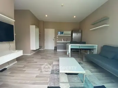 Modern living room with sleek furniture and open kitchen layout.
