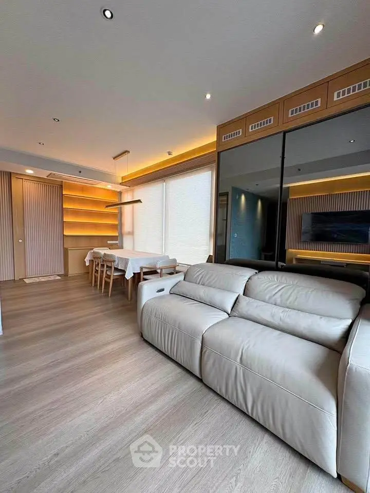 Spacious modern living room with elegant dining area and sleek wooden flooring.