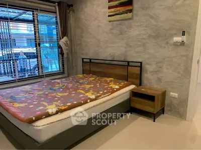Cozy bedroom with modern decor and large window offering natural light.