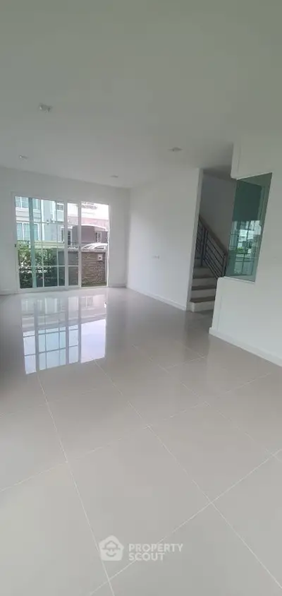 Spacious modern living room with glossy tile flooring and large windows.