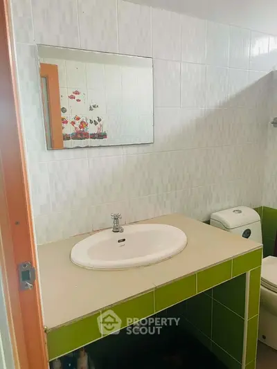 Cozy bathroom with modern sink and vibrant green tiles, perfect for a refreshing start to your day.
