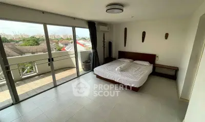 Spacious bedroom with balcony access and city view, featuring modern decor and ample natural light.