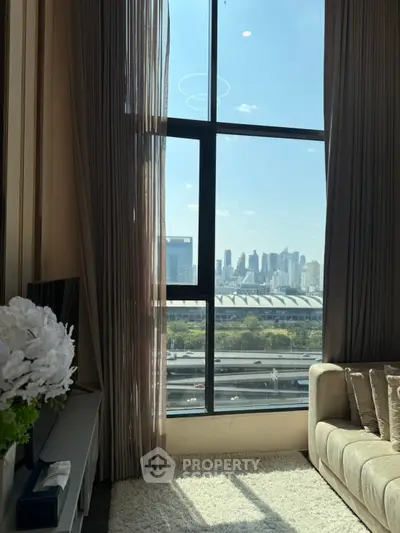 Luxurious living room with stunning city view through large windows, elegant decor and plush sofa.