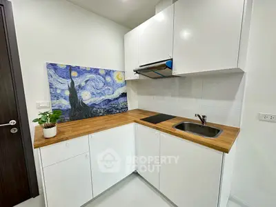 Modern kitchen with sleek white cabinets and wooden countertops, featuring a Starry Night artwork.