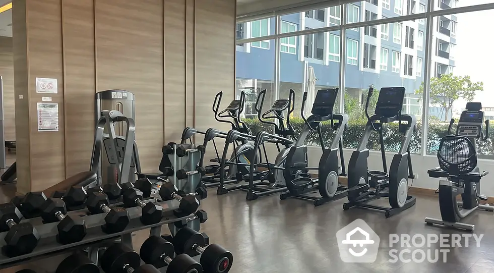 Modern gym with state-of-the-art equipment and large windows in luxury residential building.