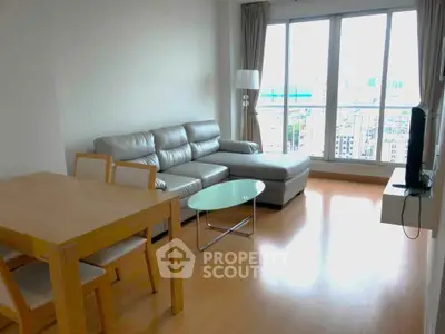 Modern living room with large windows and stylish furniture in a high-rise apartment.