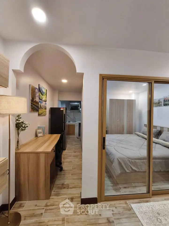 Modern apartment interior with bedroom and study area, featuring elegant decor and wooden furnishings.