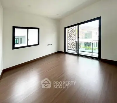 Spacious empty room with large windows and wooden flooring, perfect for customization.