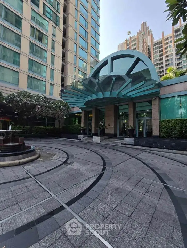 Elegant building entrance with modern architectural design and spacious driveway.