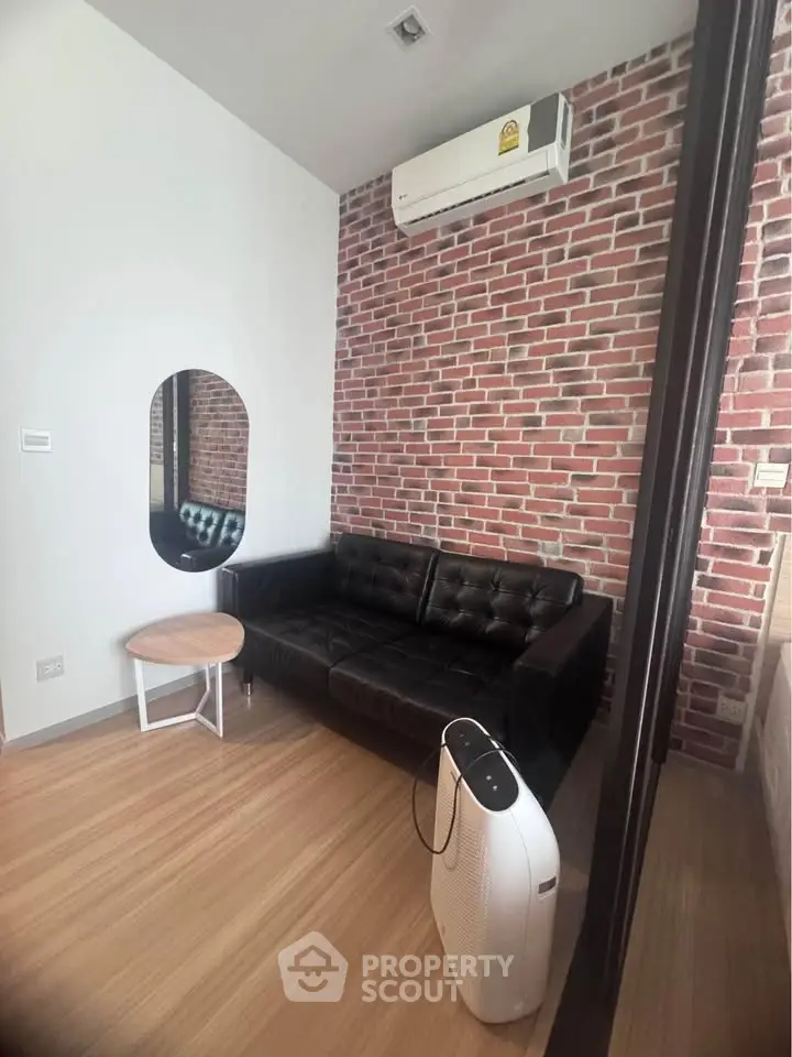 Modern living room with brick accent wall, black leather sofa, and air purifier.