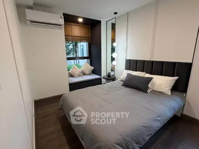 Modern bedroom with cozy bed, window seating, and stylish decor in a contemporary apartment.