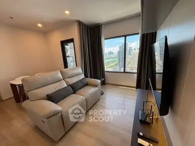 Modern living room with city view, featuring a comfortable sofa and large TV, ideal for relaxation.