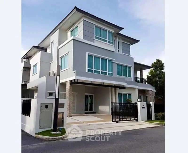 Modern three-story house with sleek design and large windows in a suburban neighborhood.