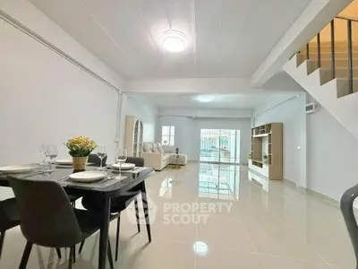 Spacious modern living room with dining area and elegant staircase, perfect for family gatherings.
