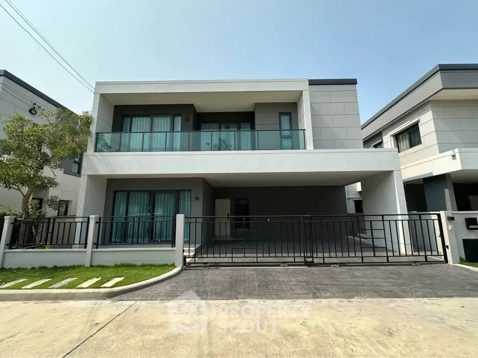 Modern two-story house with sleek design and spacious balcony in a suburban neighborhood.