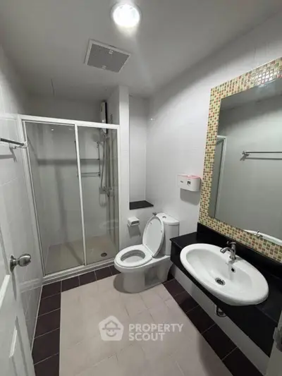 Modern bathroom with glass shower and stylish sink in a sleek apartment.