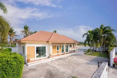 Charming single-story home with spacious driveway and lush tropical landscaping.