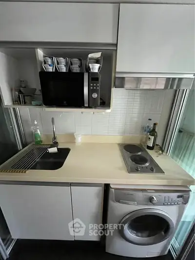 Compact kitchen with modern appliances and washing machine in a sleek design.