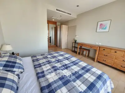 Spacious bedroom with stylish wooden furniture and cozy plaid bedding in modern apartment.