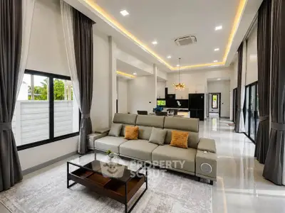 Spacious modern living room with elegant decor and open kitchen layout, featuring large windows and stylish lighting.