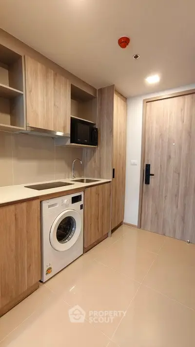 Modern kitchen with built-in appliances and washing machine in sleek apartment.