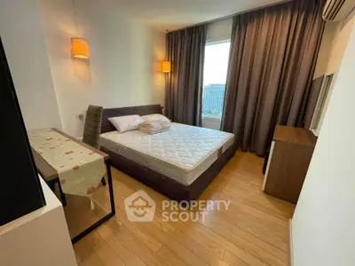 Cozy bedroom with wooden flooring, large window, and modern furnishings in a stylish apartment.
