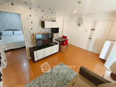 Modern living room with stylish decor and adjacent bedroom, featuring sleek furniture and wooden flooring.