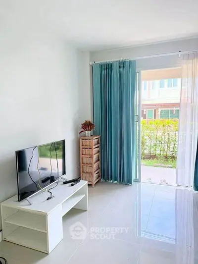 Bright living room with modern TV setup and large window overlooking garden.