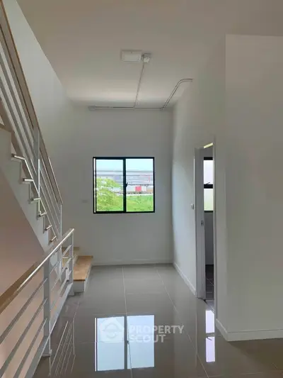 Modern minimalist interior with sleek staircase and glossy tiled floor, featuring a bright window view.