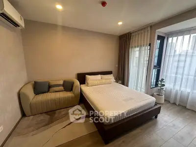 Modern bedroom with cozy bed and stylish sofa, featuring large windows and elegant curtains.