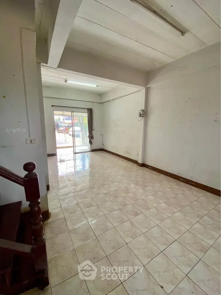 Spacious empty room with tiled floor and sliding glass door leading to balcony.